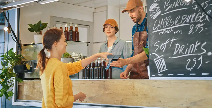 Customer is paying for their order at a food truck with their NFC-enabled smartphone