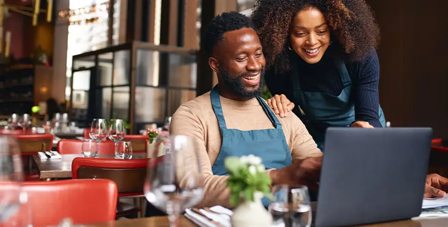 Business owners reviewing information on a laptop in their restaurant