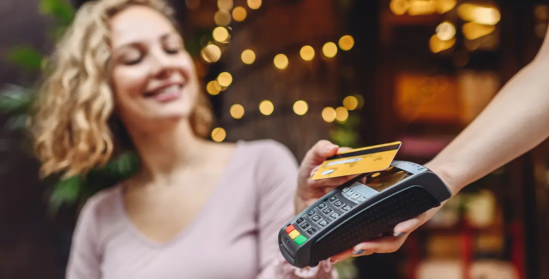 Customer paying for their order in a cafe by taping their credit card on a POS terminal