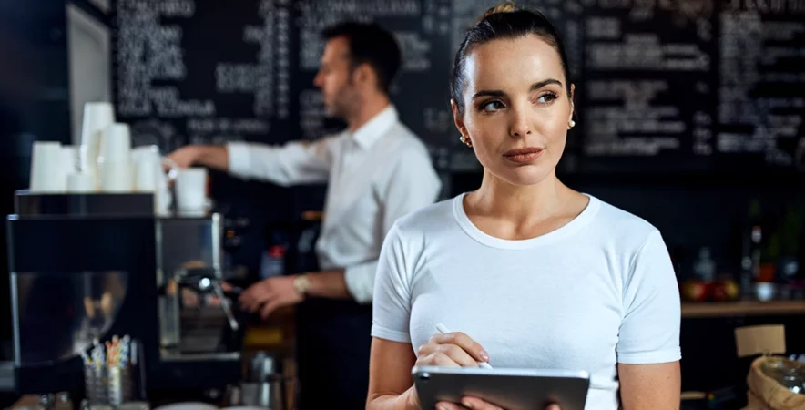 Business owner standing near a POS system, thinking about Quickbooks vs Sekure.