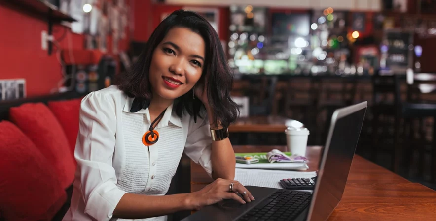 Bar owner working on laptop at the table, reviewing their payment processing solution.