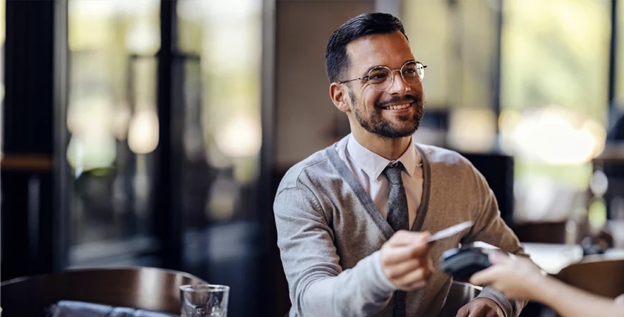 A customer paying with cashless technology in a coffee shop after the business owners updated their Verifone POS Equipment.