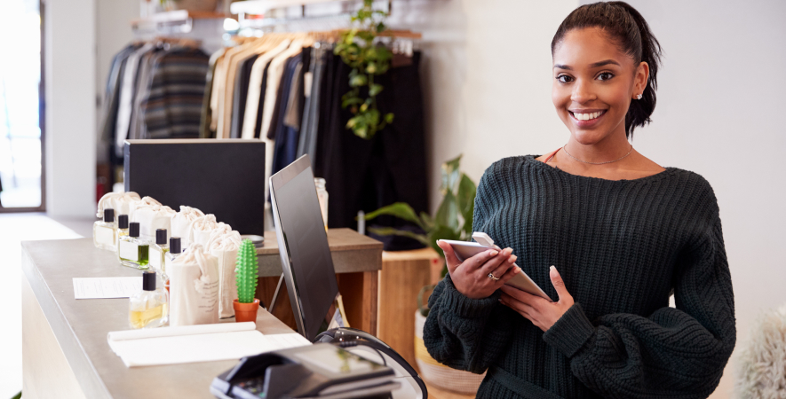 Boutique owner smiling, using POS system at store counter