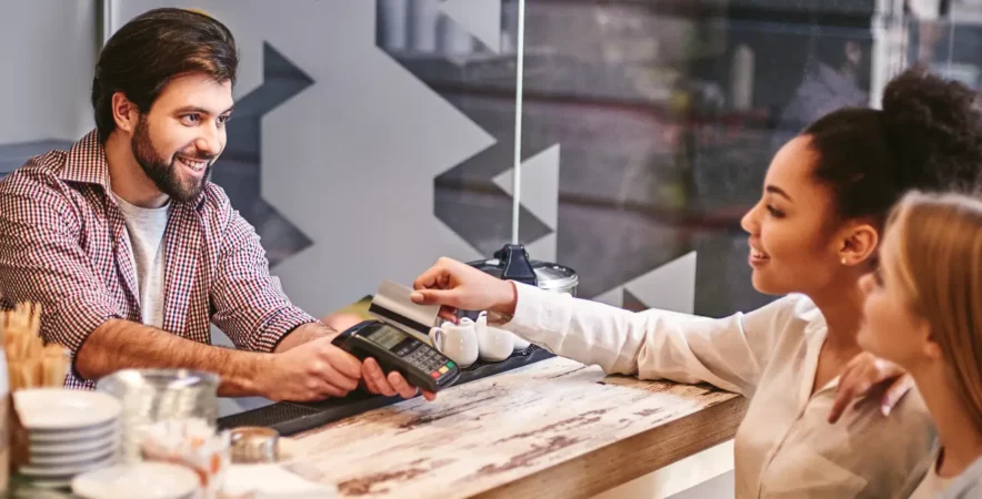 Smiling small business owner processing credit card payment at cafe