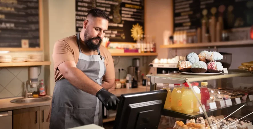 Business owner using new POS system at cafe.