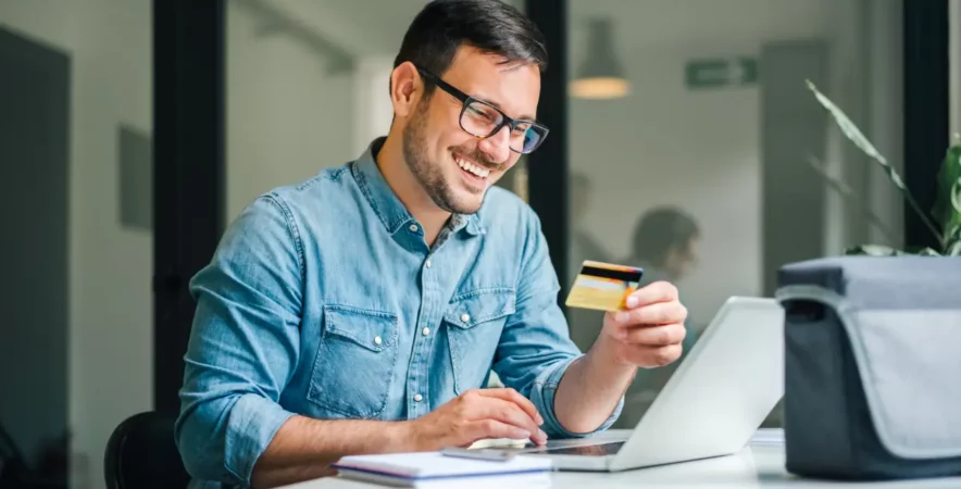 person using their credit card and laptop to make an online purchase