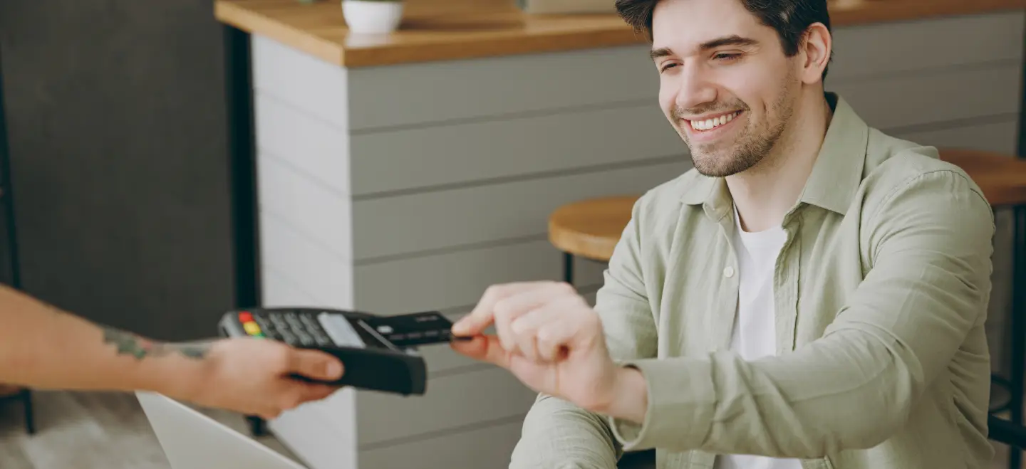 Customer paying at a cafe by tapping their card on a handheld terminal