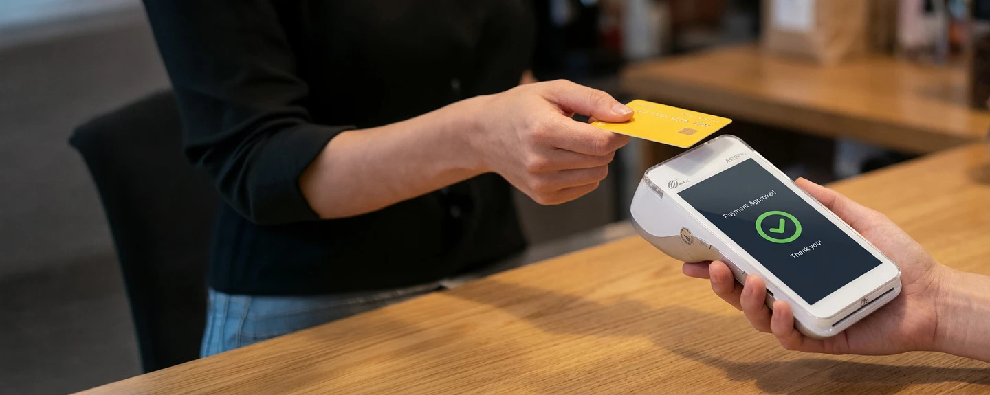 store employee holding up handheld payment terminal for the customer to tap their credit card