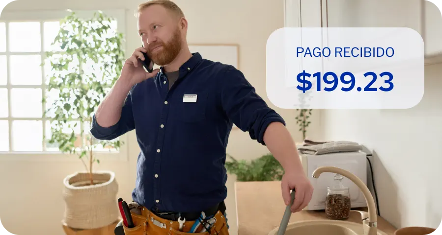 Dueño de un pequeño negocio recibiendo un pago por teléfono mientras trabaja