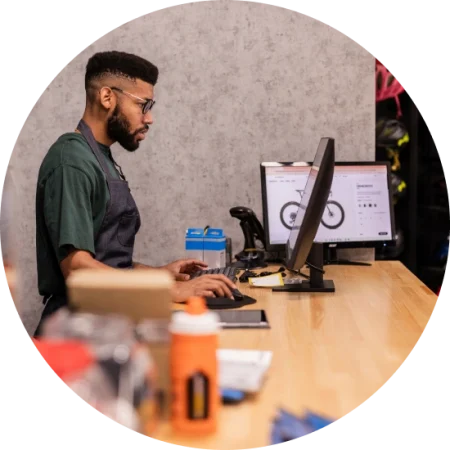 bike shop employee at the counter using the pos system on a desktop computer